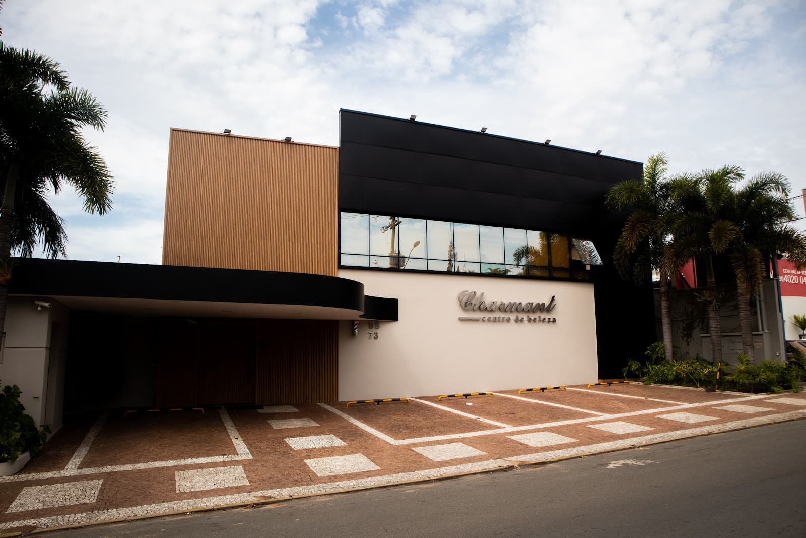Fachada da Charmant com painel de madeira e faixa preta